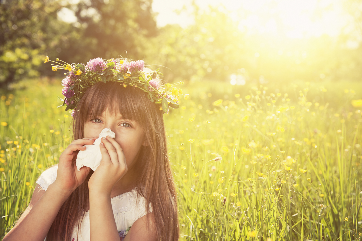 girl cleaning nose with a tissue in grass